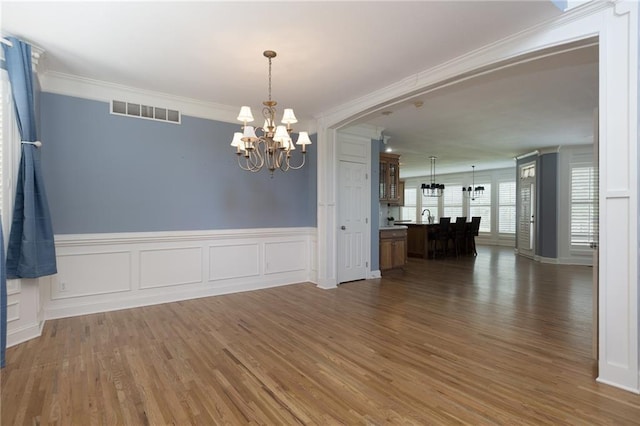 8620 N Eastern Ave, Kansas City, MO 64157 - unfurnished room featuring a chandelier, crown molding, wood finished floors, and a wainscoted wall