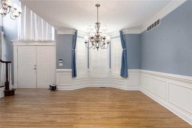 8620 N Eastern Ave, Kansas City, MO 64157 - unfurnished dining area featuring a chandelier, light wood finished floors, wainscoting, crown molding, and a decorative wall