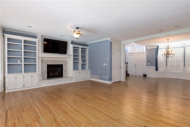 8620 N Eastern Ave, Kansas City, MO 64157 - unfurnished living room with ornamental molding, light wood-type flooring, a chandelier, a high end fireplace, and built in shelves