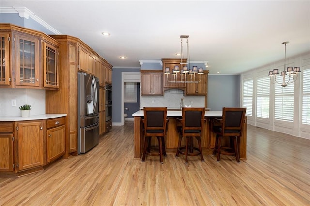 8620 N Eastern Ave, Kansas City, MO 64157 - kitchen featuring appliances with stainless steel finishes, a chandelier, brown cabinetry, crown molding, and light wood-type flooring