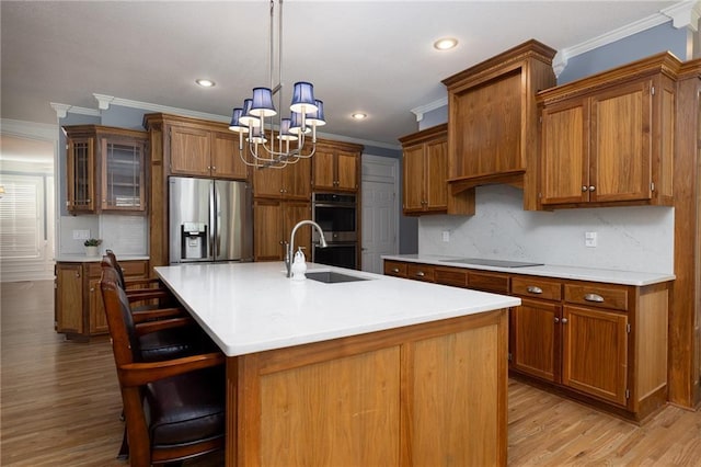 8620 N Eastern Ave, Kansas City, MO 64157 - kitchen featuring appliances with stainless steel finishes, crown molding, a chandelier, brown cabinets, and light wood finished floors