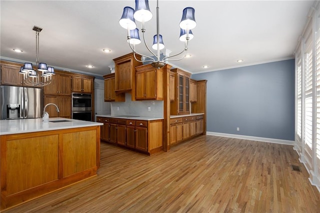 8620 N Eastern Ave, Kansas City, MO 64157 - kitchen with a chandelier, appliances with stainless steel finishes, brown cabinets, crown molding, and light countertops