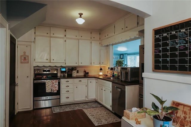 2220 Eugene Field Ave, Saint Joseph, MO 64505 - kitchen featuring appliances with stainless steel finishes, dark wood-style flooring, dark countertops, and arched walkways
