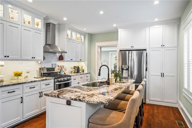 3215 Windsor Ave, Kansas City, MO 64123 - kitchen featuring wall chimney range hood, appliances with stainless steel finishes, tasteful backsplash, dark wood-style floors, and light stone counters