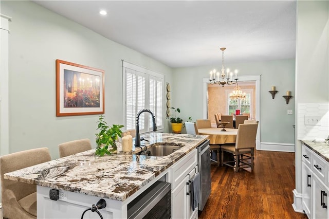 3215 Windsor Ave, Kansas City, MO 64123 - kitchen with a chandelier, dark wood-style flooring, stainless steel appliances, white cabinetry, and light stone counters