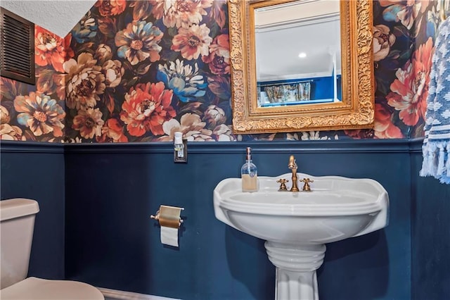3215 Windsor Ave, Kansas City, MO 64123 - bathroom with wallpapered walls, wainscoting, and a textured ceiling