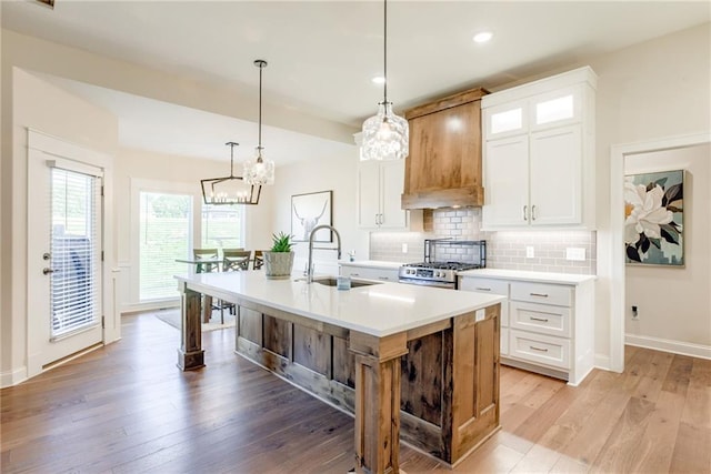 12750 Larkspur Ln, Platte City, MO 64079 - kitchen with gas range, a center island with sink, tasteful backsplash, light countertops, and light wood finished floors
