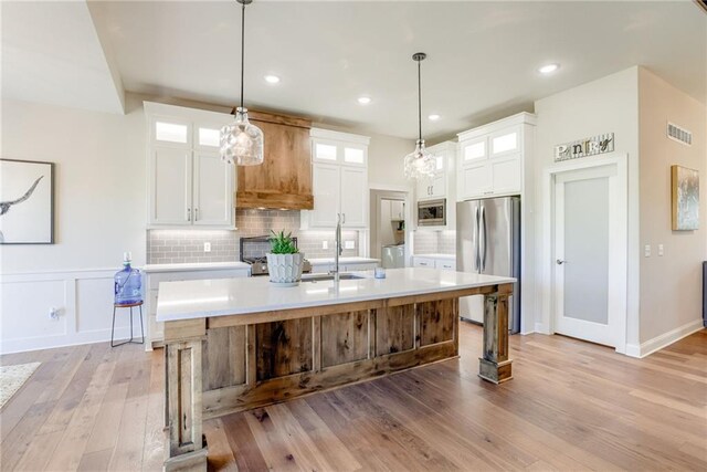 12750 Larkspur Ln, Platte City, MO 64079 - kitchen featuring appliances with stainless steel finishes, light countertops, light wood-style floors, tasteful backsplash, and recessed lighting