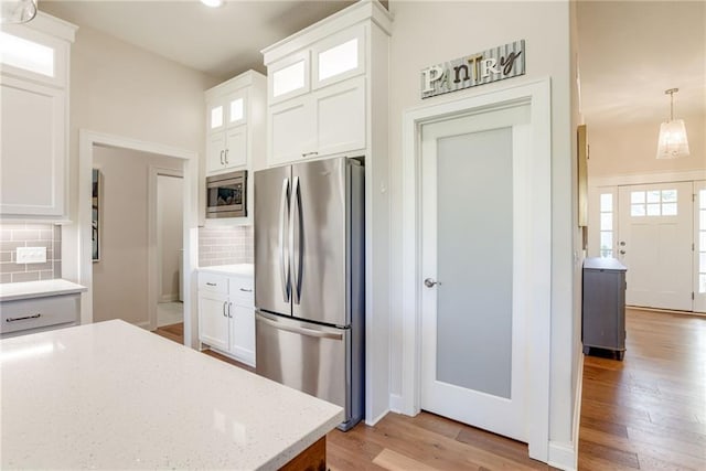 12750 Larkspur Ln, Platte City, MO 64079 - kitchen with stainless steel appliances, light wood-type flooring, white cabinetry, and backsplash