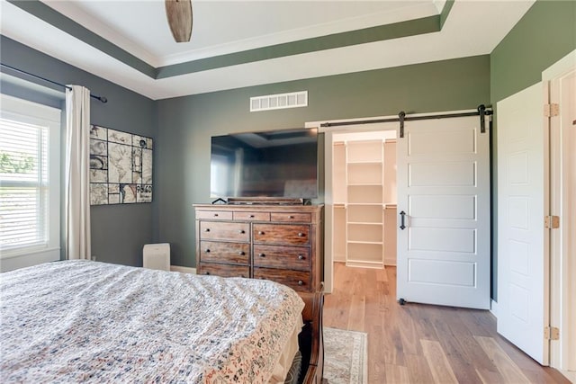 12750 Larkspur Ln, Platte City, MO 64079 - bedroom featuring a barn door, wood finished floors, a walk in closet, ornamental molding, and ceiling fan