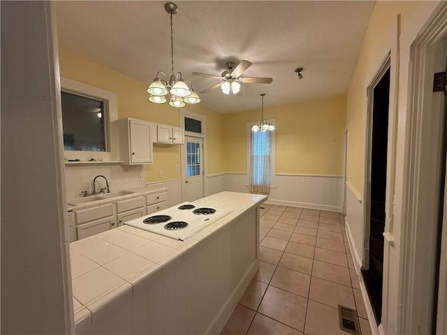 624 S St, Atchison, KS 66002 - kitchen with tile countertops, a chandelier, white cabinets, a wainscoted wall, and ceiling fan