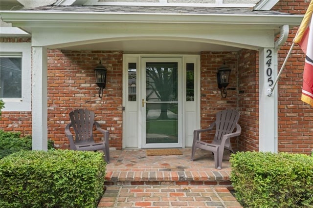 2405 W 124th St, Leawood, KS 66209 - doorway to property featuring brick siding, a porch, and roof with shingles