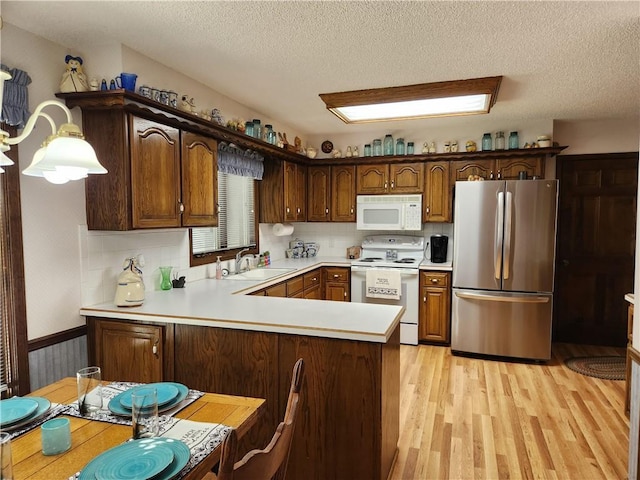 16904 E 36th St S, Independence, MO 64055 - kitchen with white appliances, light wood finished floors, light countertops, a peninsula, and a textured ceiling