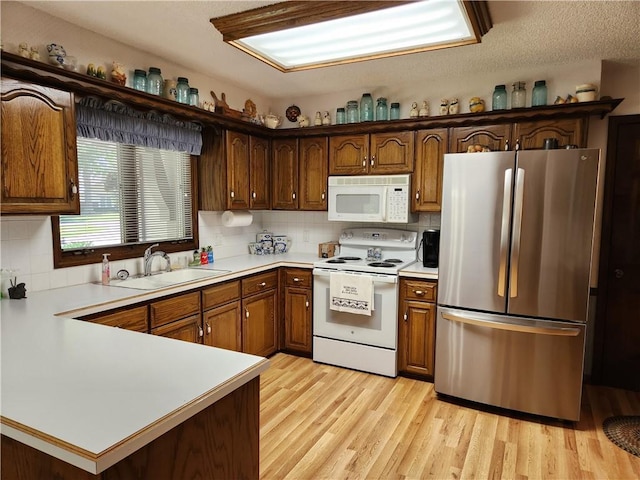 16904 E 36th St S, Independence, MO 64055 - kitchen featuring white appliances, light countertops, tasteful backsplash, light wood finished floors, and a peninsula