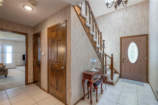 16904 E 36th St S, Independence, MO 64055 - foyer entrance featuring stairs, a textured ceiling, wallpapered walls, light tile patterned floors, and a chandelier