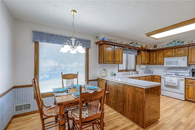 16904 E 36th St S, Independence, MO 64055 - kitchen featuring white appliances, a chandelier, a peninsula, brown cabinetry, and light wood-type flooring