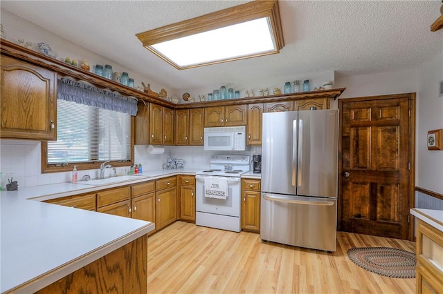 16904 E 36th St S, Independence, MO 64055 - kitchen featuring white appliances, light countertops, a textured ceiling, light wood-style floors, and decorative backsplash