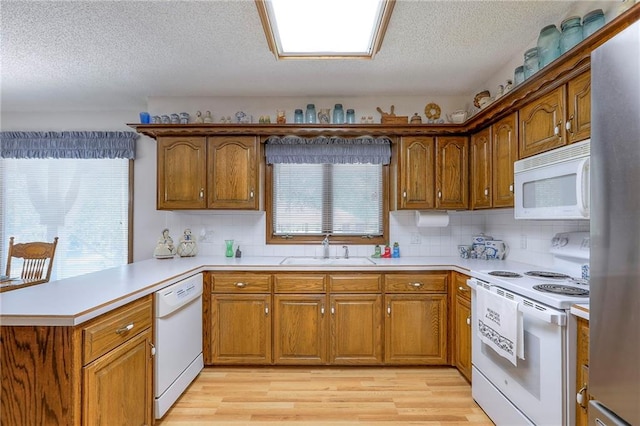 16904 E 36th St S, Independence, MO 64055 - kitchen featuring white appliances, a peninsula, brown cabinets, and a textured ceiling