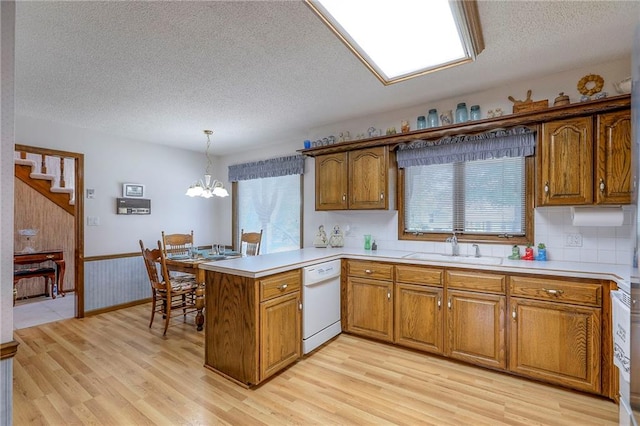 16904 E 36th St S, Independence, MO 64055 - kitchen featuring white dishwasher, a peninsula, a textured ceiling, brown cabinets, and wainscoting