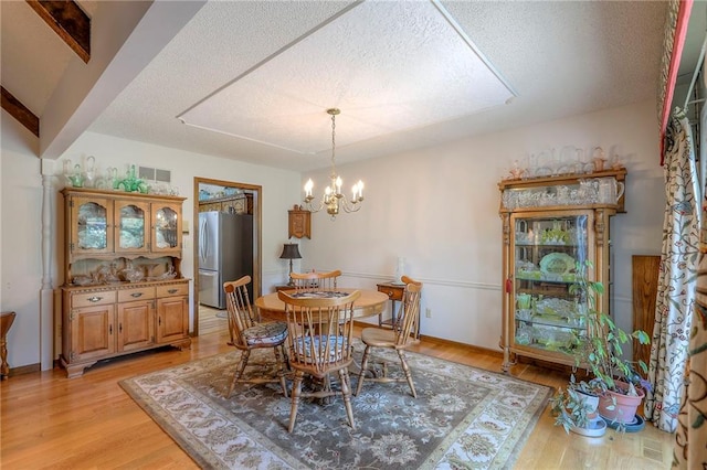 16904 E 36th St S, Independence, MO 64055 - dining space featuring a textured ceiling, light wood-type flooring, and a chandelier