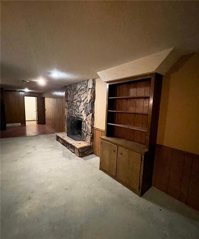 3111 N 35th St, Saint Joseph, MO 64506 - unfurnished living room featuring wooden walls, concrete flooring, a stone fireplace, and a wainscoted wall