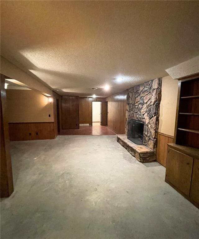 3111 N 35th St, Saint Joseph, MO 64506 - unfurnished living room with a fireplace, a textured ceiling, wood walls, and concrete floors