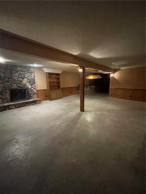 3111 N 35th St, Saint Joseph, MO 64506 - finished below grade area featuring a stone fireplace, wood walls, a textured ceiling, and a wainscoted wall
