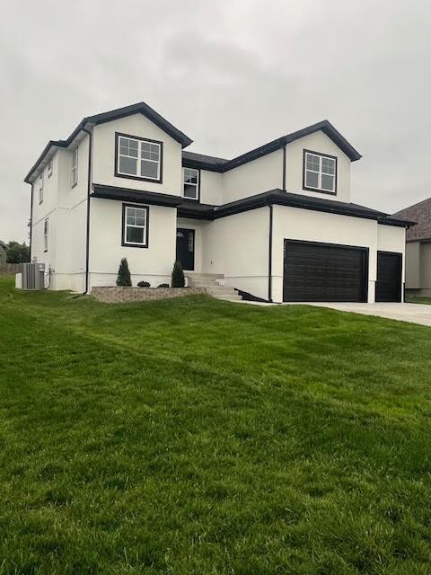 26433 W 144th Ter, Olathe, KS 66061 - view of front of home with an attached garage, a front yard, driveway, and stucco siding