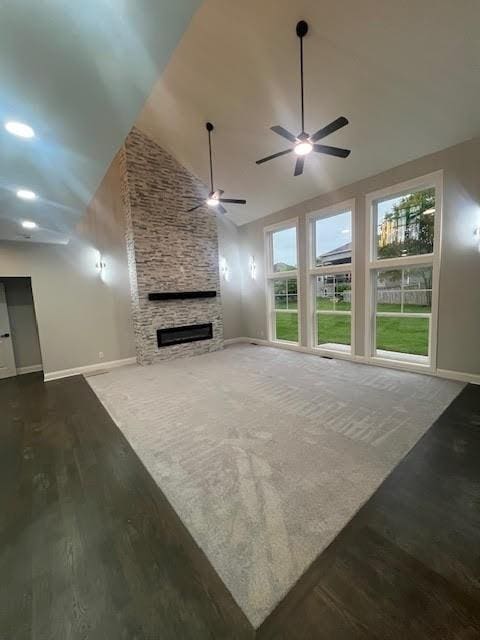 26433 W 144th Ter, Olathe, KS 66061 - unfurnished living room featuring a ceiling fan, wood finished floors, high vaulted ceiling, and a stone fireplace