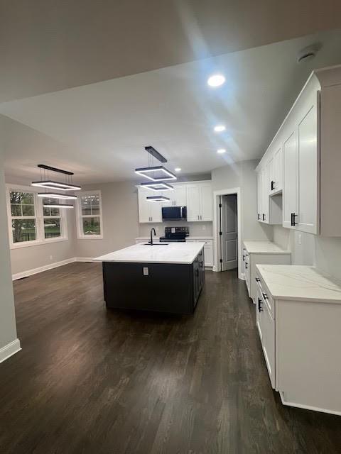 26433 W 144th Ter, Olathe, KS 66061 - kitchen with stainless steel microwave, stove, a center island with sink, light countertops, and dark wood-style flooring