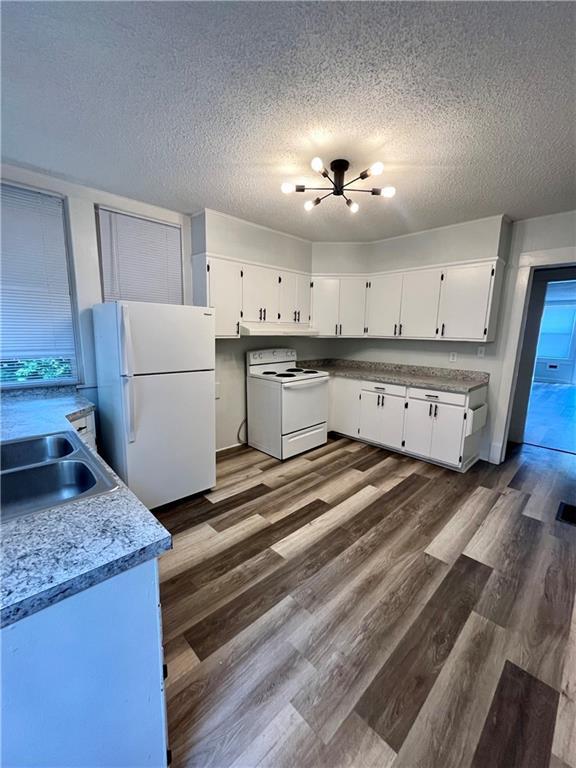 2830 Jules St, Saint Joseph, MO 64501 - kitchen featuring white appliances, a textured ceiling, white cabinets, dark wood-style flooring, and light countertops