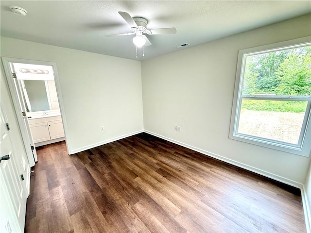719 E Culton St, Warrensburg, MO 64093 - unfurnished bedroom with dark wood-style floors, connected bathroom, and a ceiling fan