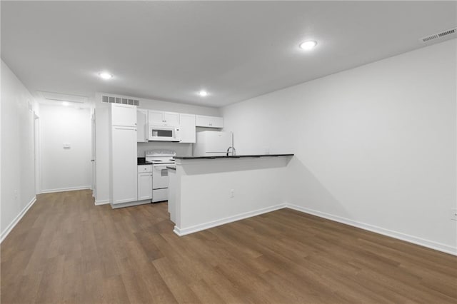 719 E Culton St, Warrensburg, MO 64093 - kitchen with white appliances, dark wood-type flooring, a peninsula, white cabinetry, and dark countertops