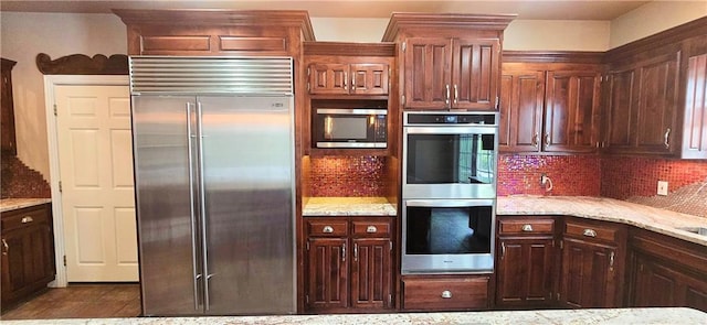 789 Maple Rd, Uniontown, KS 66779 - kitchen featuring appliances with stainless steel finishes, tasteful backsplash, and light stone counters