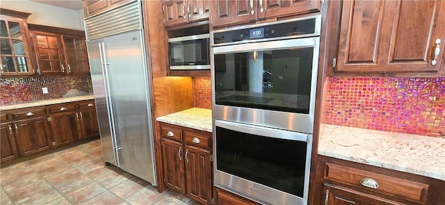 789 Maple Rd, Uniontown, KS 66779 - kitchen with stainless steel appliances, tasteful backsplash, glass insert cabinets, and light stone counters
