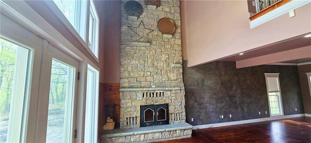 789 Maple Rd, Uniontown, KS 66779 - unfurnished living room featuring wood-type flooring, a stone fireplace, and a towering ceiling