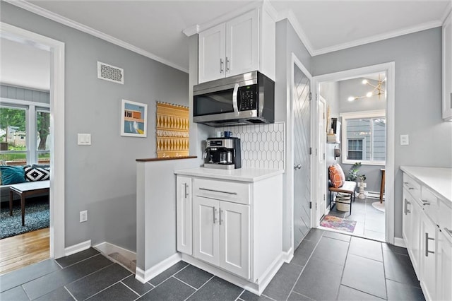 5001 W 70th St, Prairie Village, KS 66208 - kitchen featuring stainless steel microwave, white cabinetry, tasteful backsplash, ornamental molding, and dark tile patterned flooring