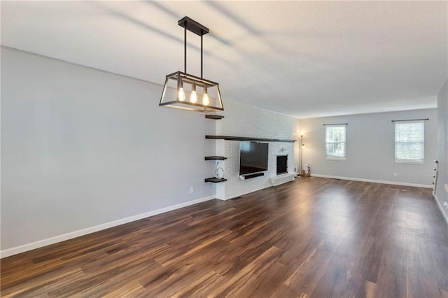 10017 W 95th St, Overland Park, KS 66212 - unfurnished living room featuring dark wood-style floors, a brick fireplace, a textured ceiling, and a chandelier