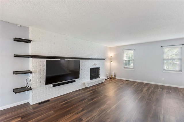 10017 W 95th St, Overland Park, KS 66212 - unfurnished living room with a brick fireplace, wood finished floors, and a textured ceiling