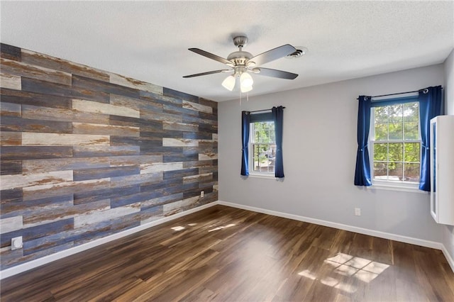 10017 W 95th St, Overland Park, KS 66212 - empty room featuring wooden walls, plenty of natural light, an accent wall, wood finished floors, and ceiling fan
