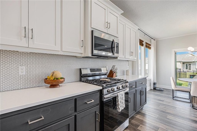 20854 W 190th Pl, Spring Hill, KS 66083 - kitchen with appliances with stainless steel finishes, light countertops, backsplash, light wood finished floors, and ornamental molding