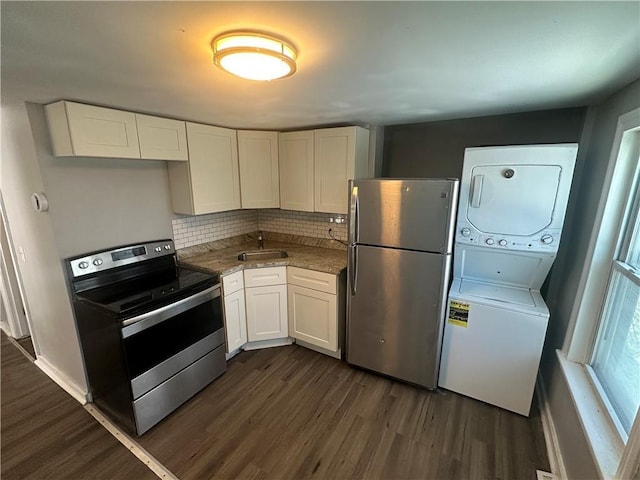 11300 E 29th St, Independence, MO 64052 - kitchen featuring appliances with stainless steel finishes, stacked washer / drying machine, dark wood finished floors, white cabinets, and decorative backsplash
