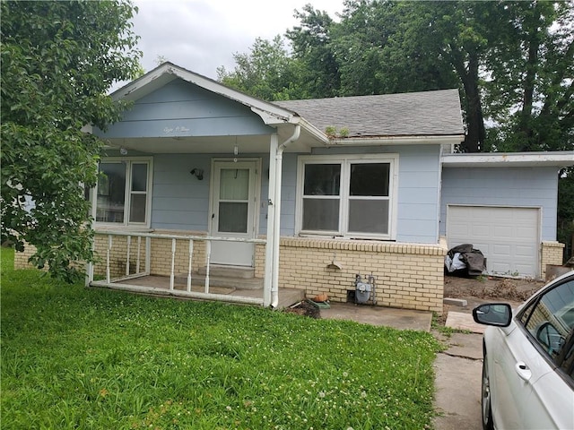 809 W 1st St, Coffeyville, KS 67337 - bungalow with an attached garage, a porch, a front lawn, brick siding, and roof with shingles