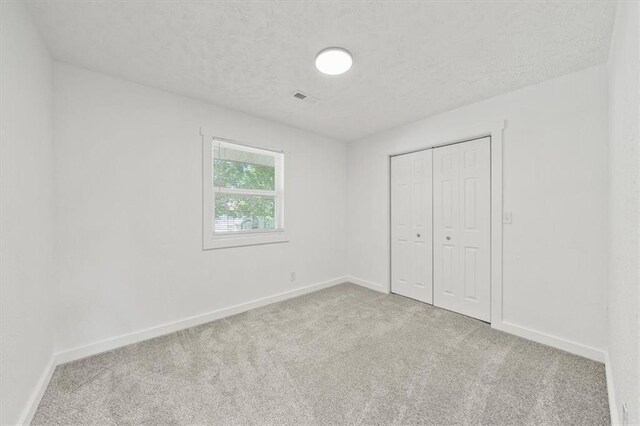 1000 Twin Oaks Ter, Harrisonville, MO 64701 - unfurnished bedroom with carpet, a textured ceiling, and a closet