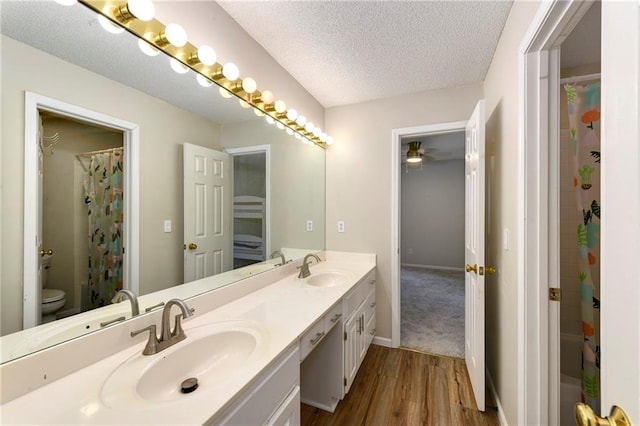 14010 Ash St, Overland Park, KS 66224 - bathroom with double vanity, wood finished floors, a textured ceiling, and curtained shower
