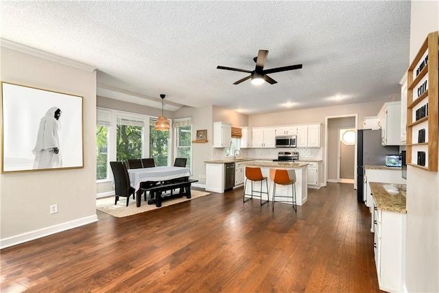 14010 Ash St, Overland Park, KS 66224 - kitchen with stainless steel appliances, white cabinetry, a kitchen island, a textured ceiling, and a ceiling fan
