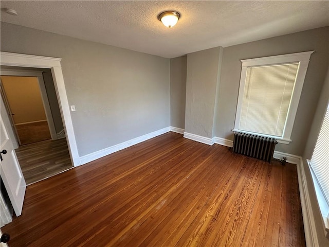 726 N River Blvd, Independence, MO 64050 - unfurnished room with radiator heating unit, wood finished floors, a textured ceiling, and a smoke detector