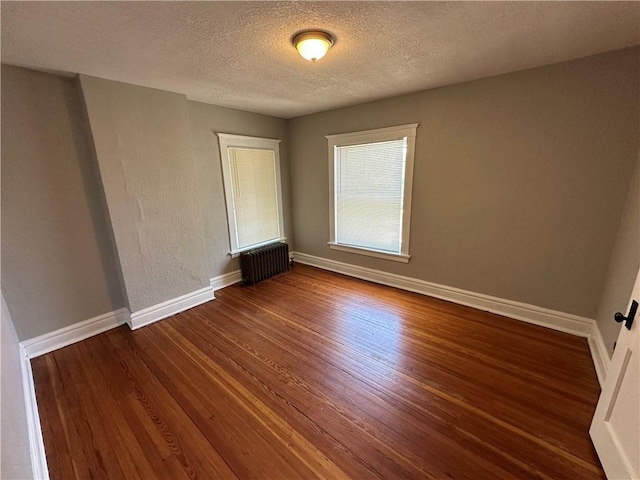 726 N River Blvd, Independence, MO 64050 - unfurnished room featuring radiator heating unit, dark wood-style flooring, and a textured ceiling