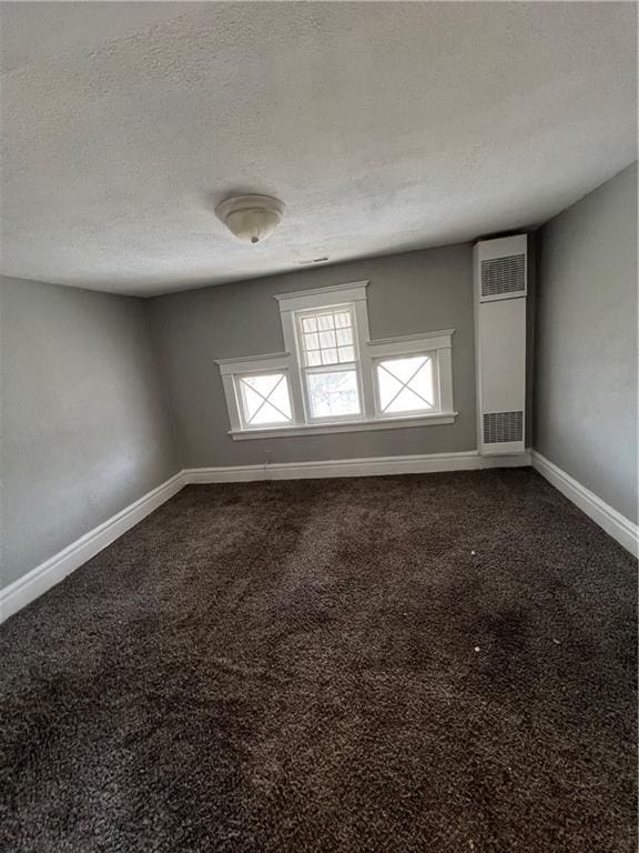 726 N River Blvd, Independence, MO 64050 - unfurnished room featuring a heating unit, dark colored carpet, and a textured ceiling