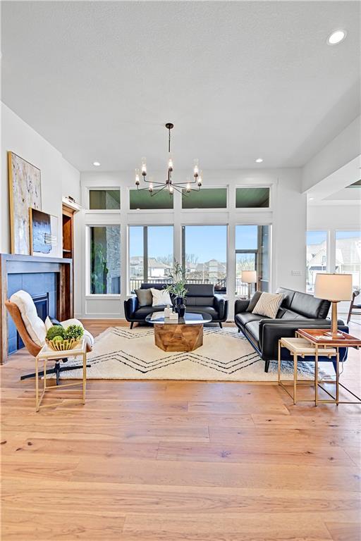 17404 Crystal St, Overland Park, KS 66221 - living area featuring a chandelier, light wood-style floors, a glass covered fireplace, and recessed lighting